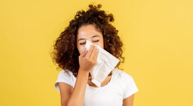 Eine Frau putzt ihre Nase mit einem Taschentuch